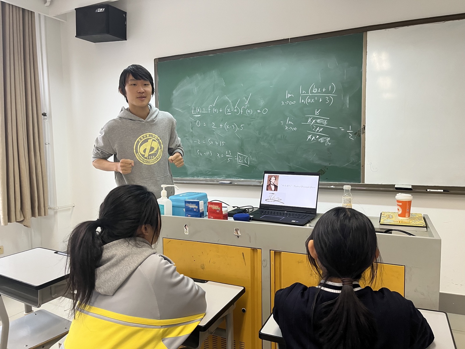 Students listening while James speaks near the blackboard.