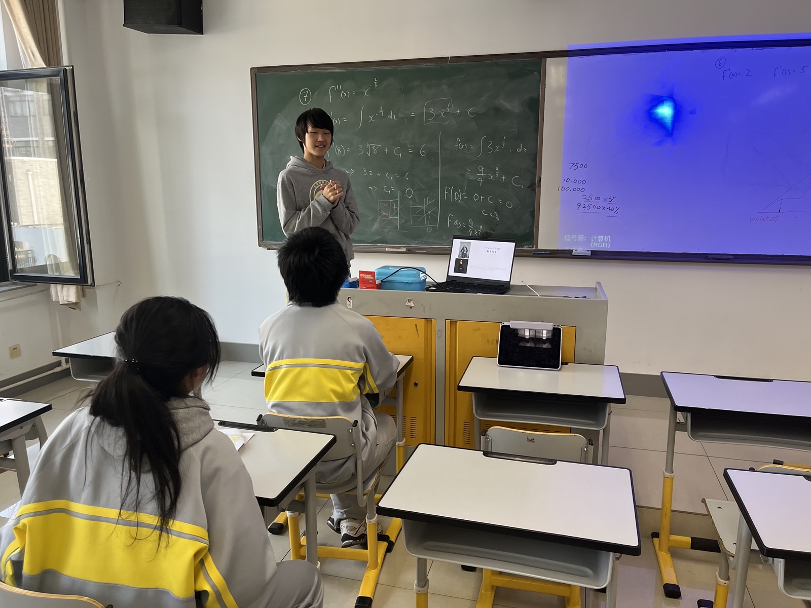 James presenting while classmates sit at desks.