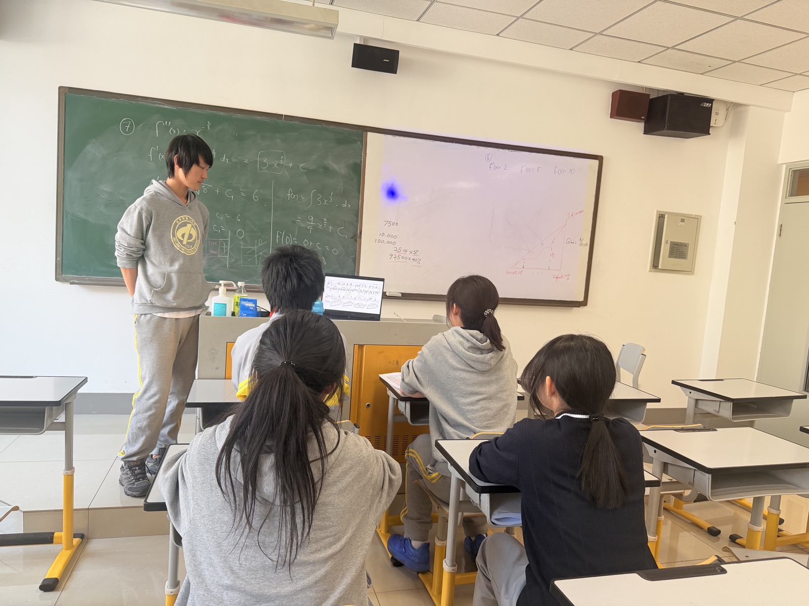 A small group of students listening to a musical score on a laptop.